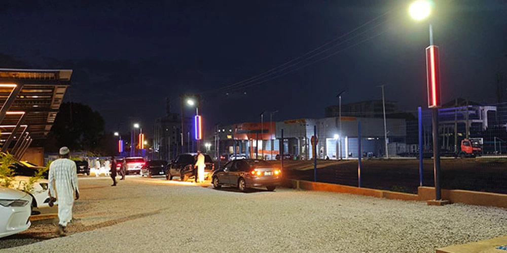 Parking lot light pole with a white pole-top lamp and separate decorative light strips at night